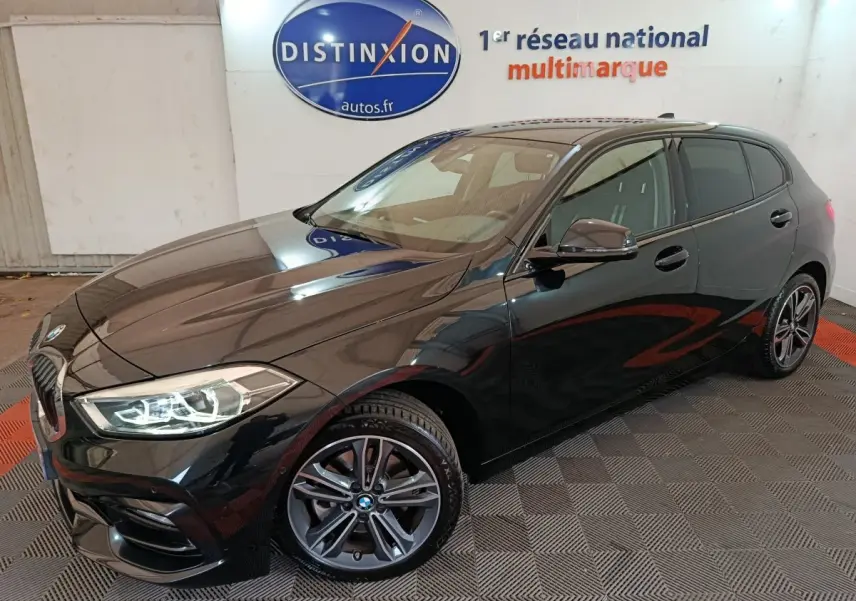BMW Série 1 118i Edition Sport noire vue en 3/4 avant, phares LED allumés et jantes alliage distinctives.
