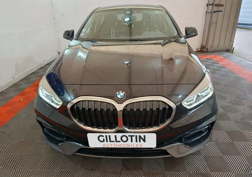 Vue avant rapprochée d’une BMW Série 1 118i Edition Sport noire avec calandre double haricot et phares LED allumés.