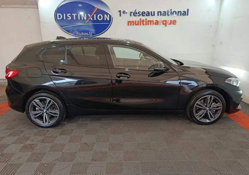 BMW Série 1 118i Edition Sport noire vue de profil côté gauche, jantes alliage et feux arrière LED visibles.