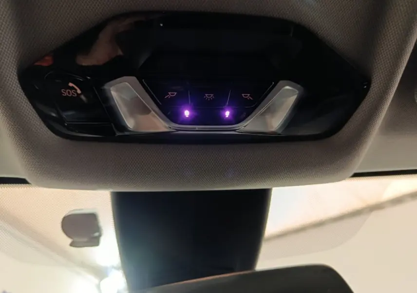 Vue intérieure du plafonnier avec boutons de commande et éclairage violet sur BMW Série 1 118i Edition Sport noire 2023.