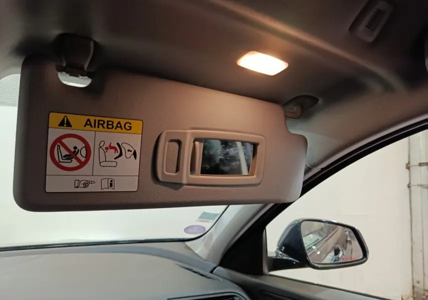 Détail intérieur côté conducteur de la BMW Série 1 noire 2023 montrant le pare-soleil avec miroir et éclairage.
