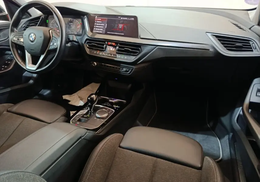 Intérieur BMW Série 1 118i Edition Sport 2023, vue de face côté conducteur, tableau de bord et console noire moderne.