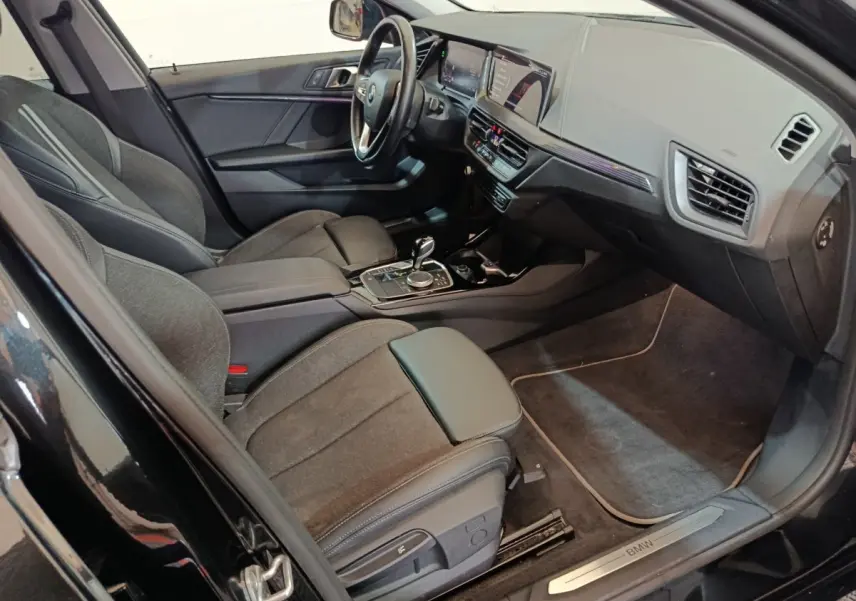 Intérieur noir de la BMW Série 1 118i Edition Sport 2023, vue côté conducteur avec tableau de bord et console centrale.