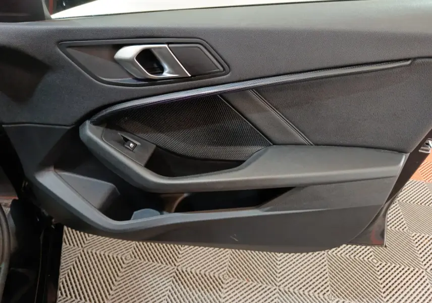 Gros plan sur la porte intérieure côté conducteur noire de la BMW Série 1 118i Edition Sport avec poignée argentée.