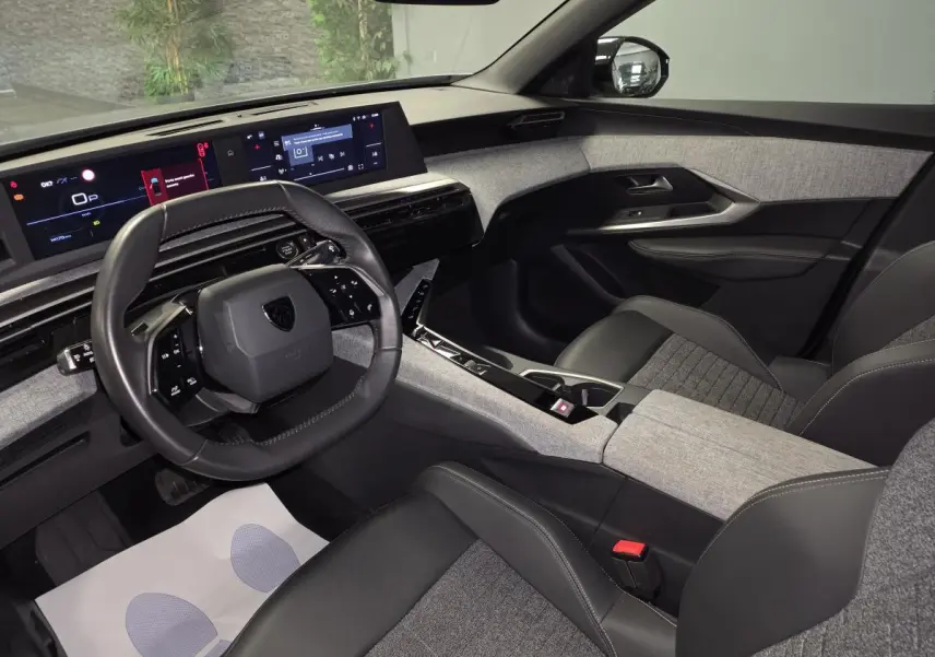 Intérieur gris et noir du Peugeot 3008 2025, vue côté conducteur, avec tableau de bord numérique et volant compact cuir.
