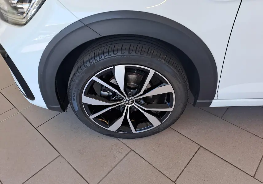 Gros plan sur la roue avant gauche du Volkswagen Taigo blanc pur avec jante alliage noir et argent "Misano" 18 pouces.
