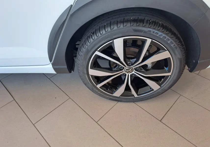 Gros plan sur la jante alliage 18 pouces bicolore du côté arrière droit d’un Volkswagen Taigo blanc pur.