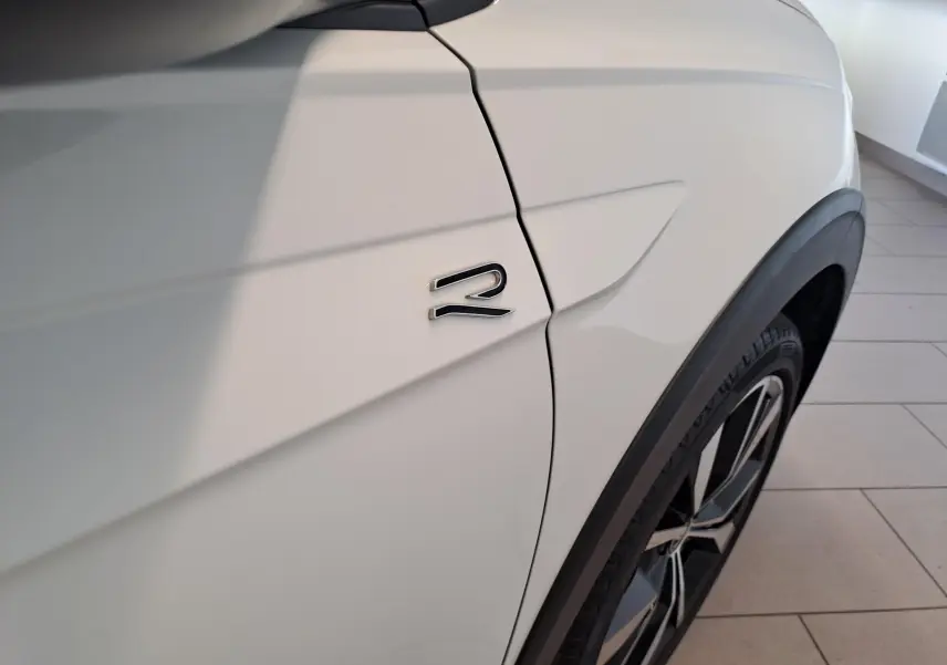 Détail du côté avant droit du Volkswagen Taigo blanc pur, avec logo R-LINE et jante alliage 18 pouces.