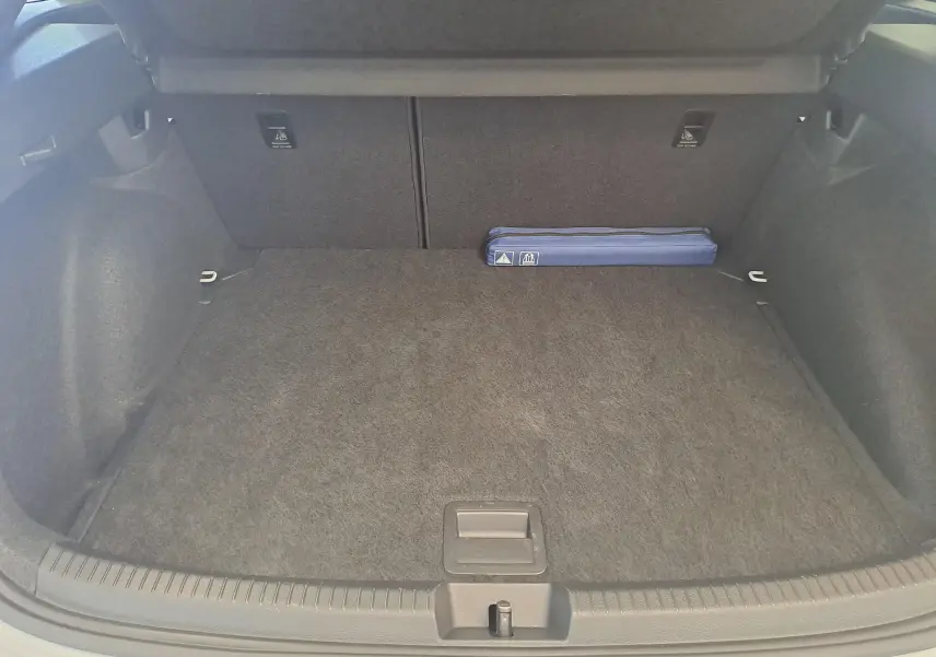 Vue intérieure du coffre spacieux du Volkswagen Taigo blanc pur 2025, avec un kit de sécurité bleu posé à l'arrière.