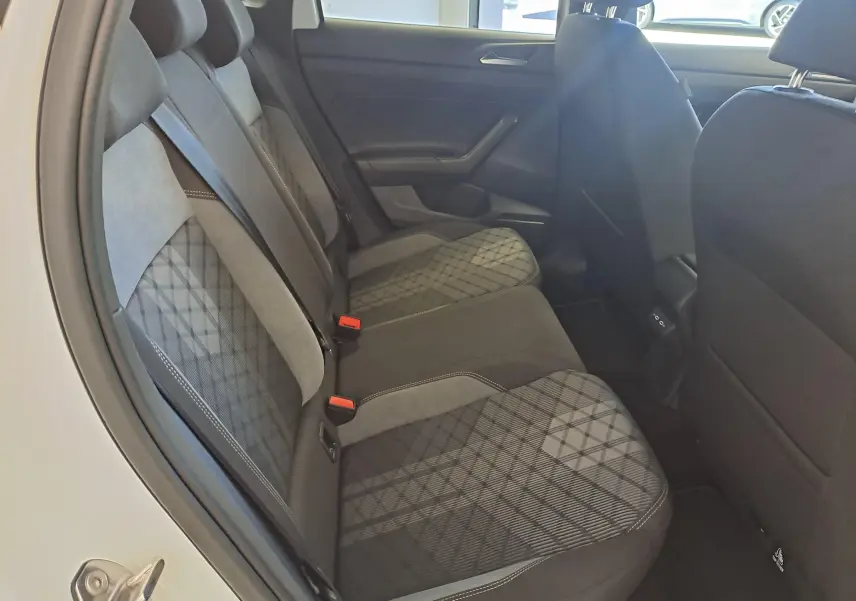 Vue intérieure arrière gauche du Volkswagen Taigo 2025, sièges en tissu noir et gris avec motifs géométriques.