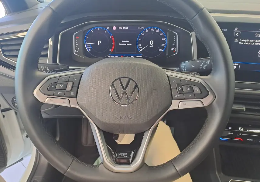 Vue rapprochée du volant multifonction noir avec logo Volkswagen et tableau de bord numérique du Taigo 2025.