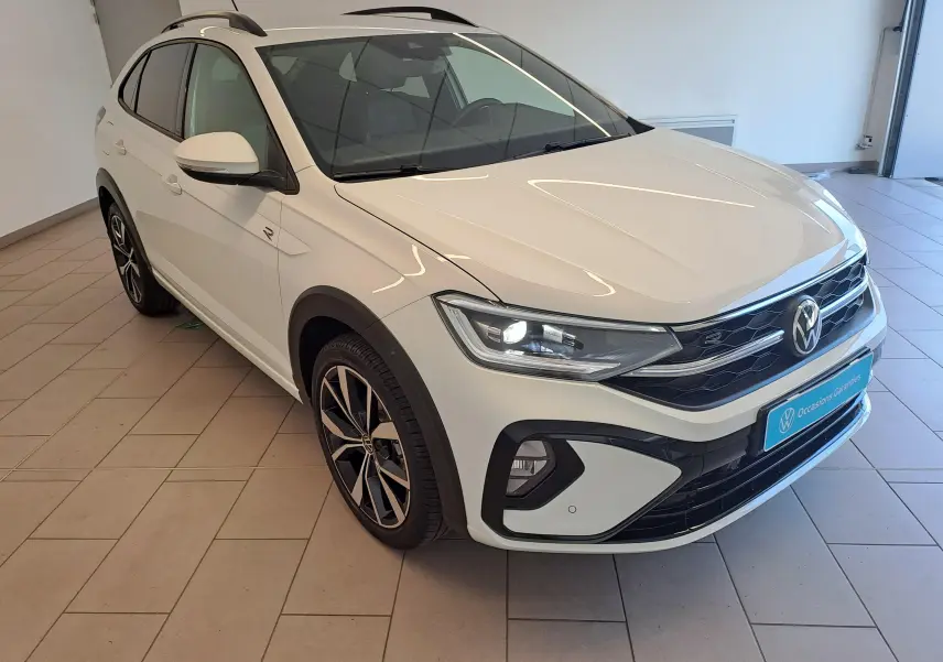 Volkswagen Taigo blanc pur en vue 3/4 avant droit, avec jantes alliage 18 pouces et détails R-Line visibles.