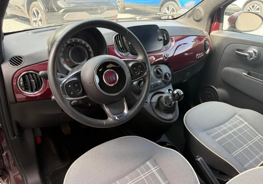 Vue intérieure côté conducteur de la FIAT 500 violet 2019, volant cuir multifonctions et tableau de bord brillant.