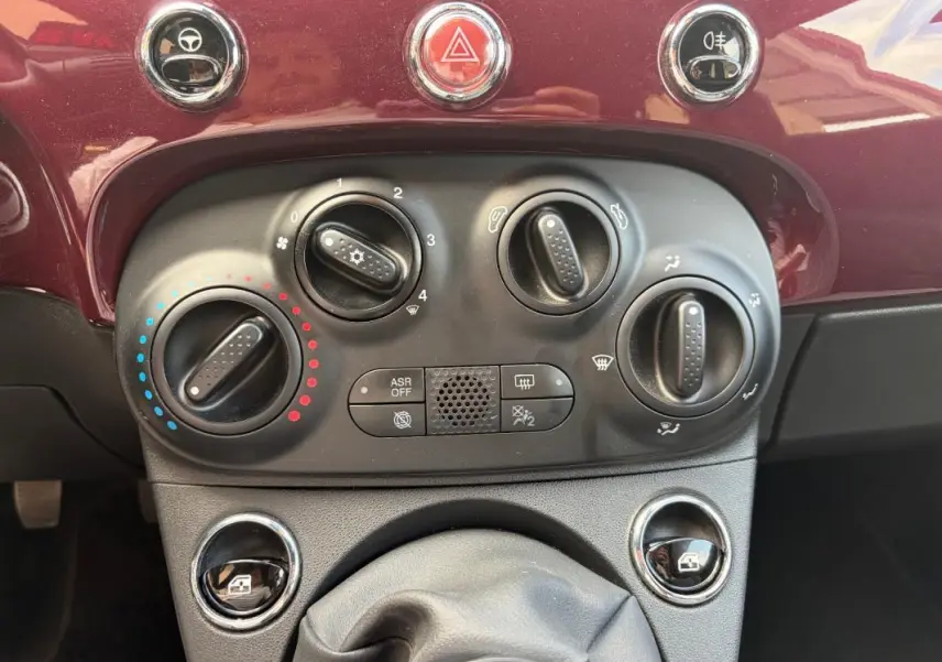 Vue rapprochée des commandes de climatisation et ventilation sur le tableau de bord violet de la Fiat 500 Lounge 2019.