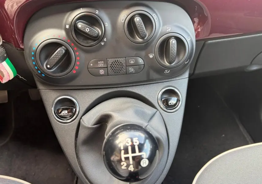 Vue rapprochée de la console centrale violette d'une Fiat 500 2019 avec commandes de climatisation et levier de vitesse manuel.