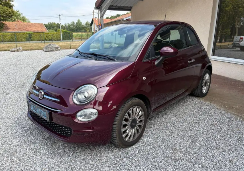 Vue 3/4 avant droit d'une FIAT 500 berline violet foncé 2019 avec jantes alliage et rétroviseurs assortis.