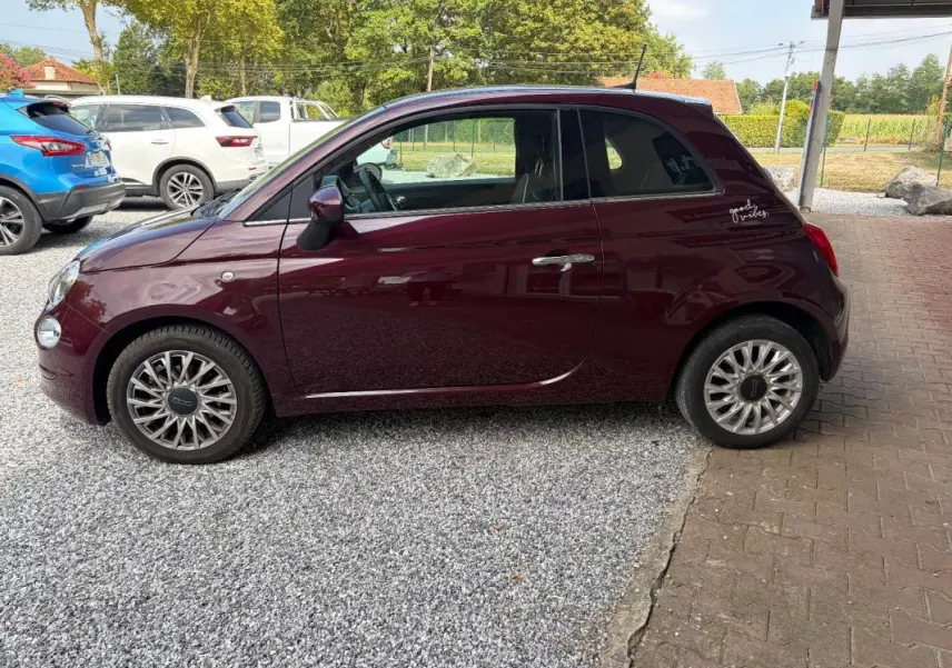 Profil côté gauche d'une FIAT 500 berline violet foncé de 2019 avec jantes alliage et sticker "good vibes" arrière.