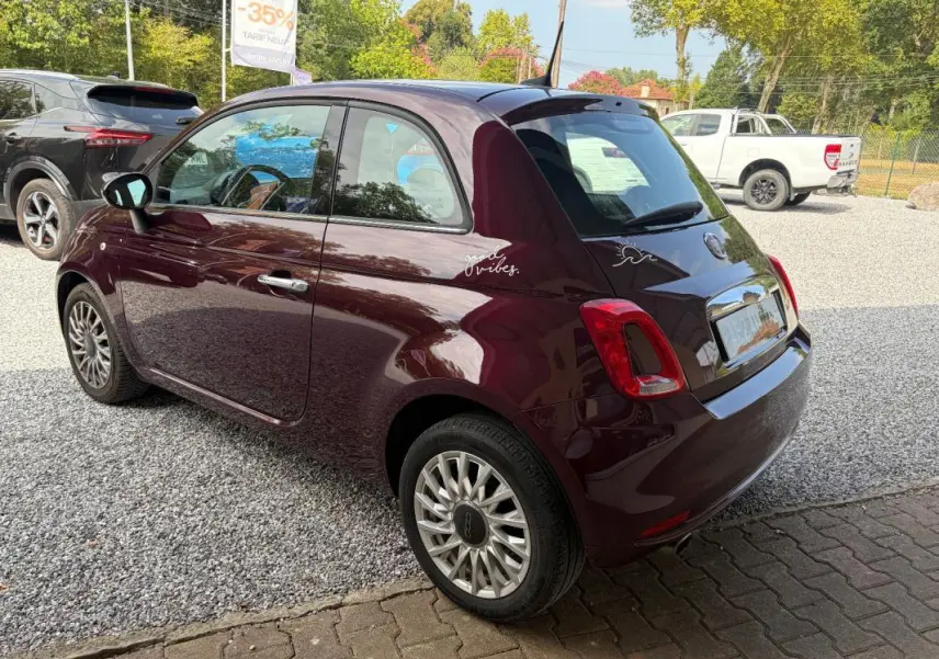 Vue 3/4 arrière droite d'une FIAT 500 berline violet foncé avec jantes alliage et stickers décoratifs sur l'aile arrière.