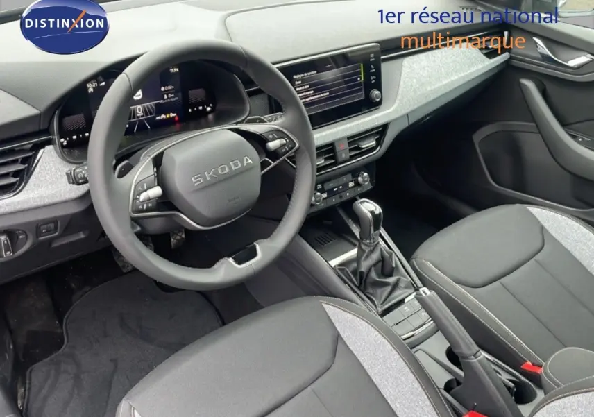 Intérieur du Skoda Kamiq 2025 vu côté conducteur, avec volant multifonction et sellerie tissu gris noir.