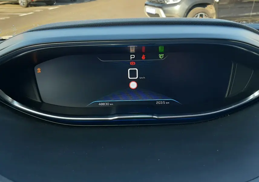 Vue rapprochée du tableau de bord numérique du Peugeot 3008 gris Amazonite, affichant la vitesse à 0 km/h et les voyants allumés.