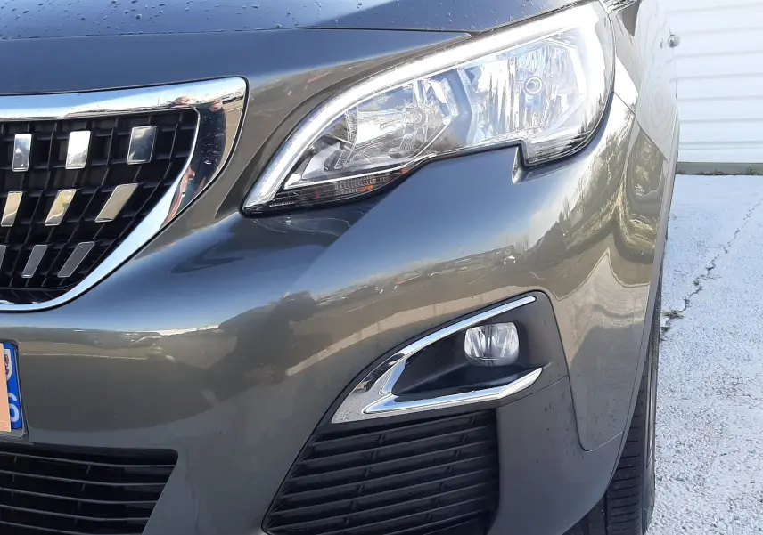Vue 3/4 avant droit d'un Peugeot 3008 gris amazonite avec phares LED et calandre chromée brillante.