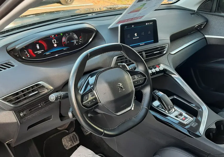 Vue intérieure côté conducteur du Peugeot 3008 gris Amazonite, mettant en valeur le volant compact, l'écran tactile central et la console moderne.