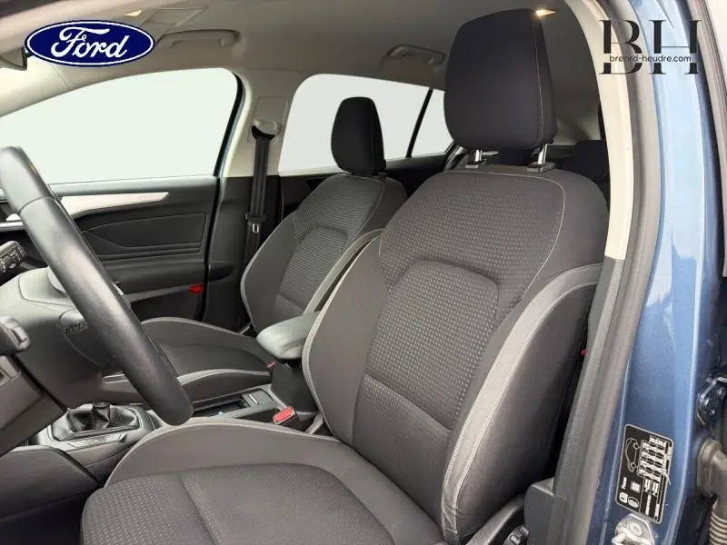 Vue intérieure côté gauche de la Ford Focus SW 2019, sièges tissu noir avec surpiqûres grises, portière bleu azur métallisé visible.