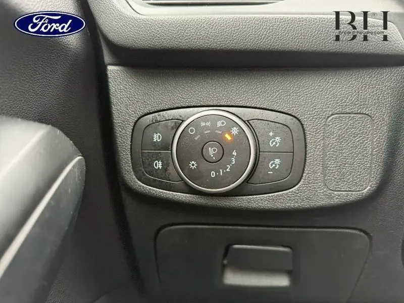 Gros plan sur la commande d’éclairage noire du tableau de bord d’une Ford Focus SW 2019, intérieur noir.