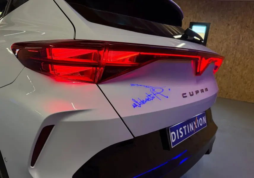 Vue 3/4 arrière droite du CUPRA Formentor blanc avec feux arrière allumés et logo CUPRA visible sur le hayon.