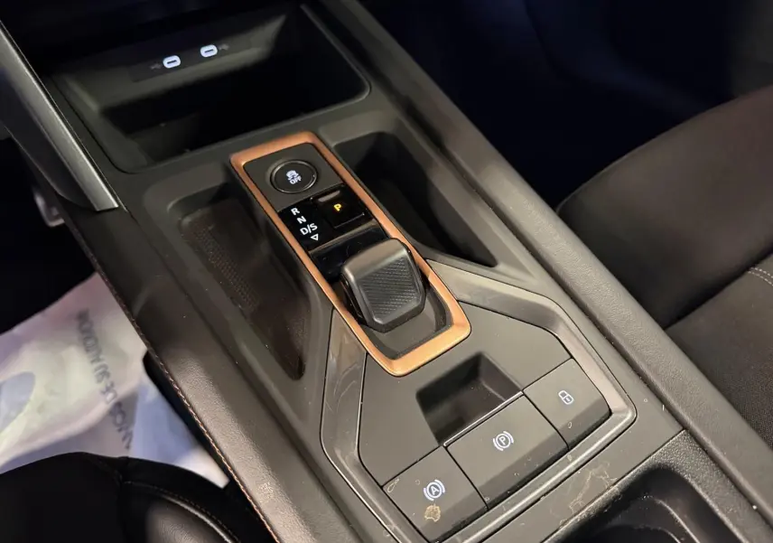 Gros plan sur la console centrale noire avec levier de vitesses automatique et cadre cuivre dans un CUPRA Formentor blanc.