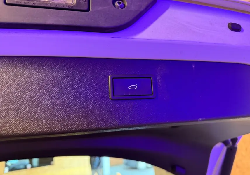 Gros plan sur le bouton d'ouverture électrique du hayon, sur la partie intérieure blanche du coffre du CUPRA Formentor blanc.