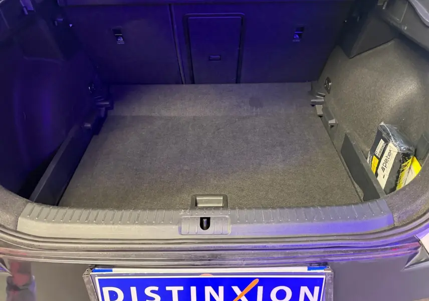 Vue du coffre ouvert d'un CUPRA Formentor blanc 2025, montrant un espace de chargement propre avec un kit de secours sur le côté droit.