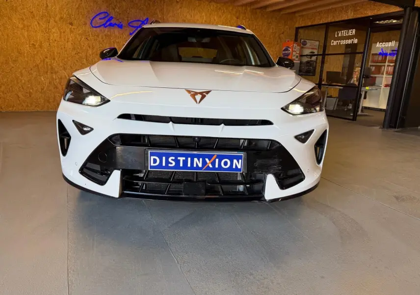 Vue frontale d’un CUPRA Formentor blanc 2025 avec logo cuivré et calandre noire dans un showroom.