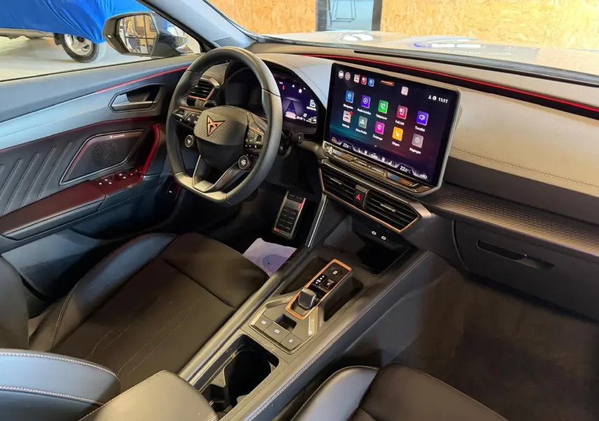 Vue intérieure côté conducteur de la CUPRA Formentor 2025, volant Supersports, écran tactile HD et finitions noires avec surpiqûres rouges.