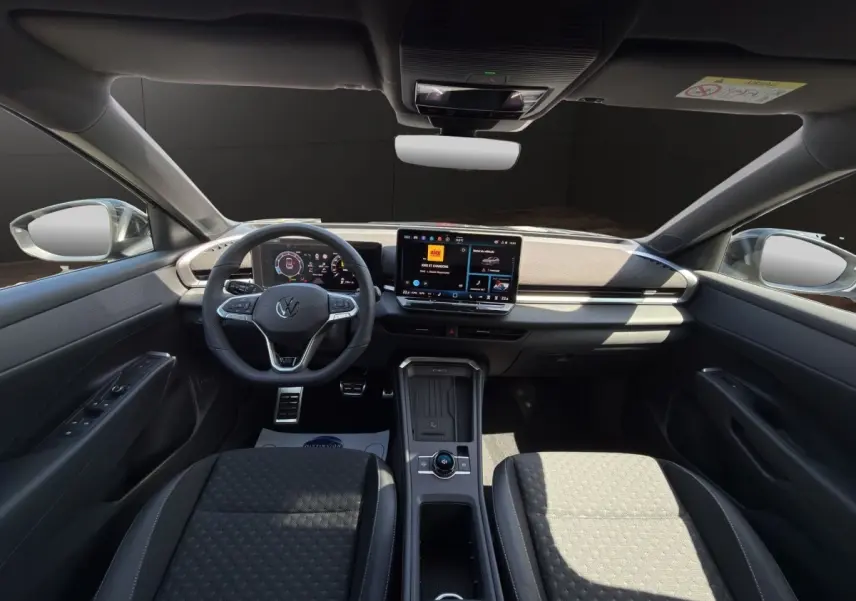 Vue intérieure avant du Volkswagen T-Roc noir 2026, mettant en valeur le tableau de bord digital et l'écran tactile central.
