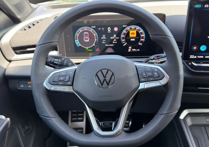 Vue rapprochée du volant cuir noir multifonctions du Volkswagen T-Roc 2026 avec tableau de bord numérique affiché.