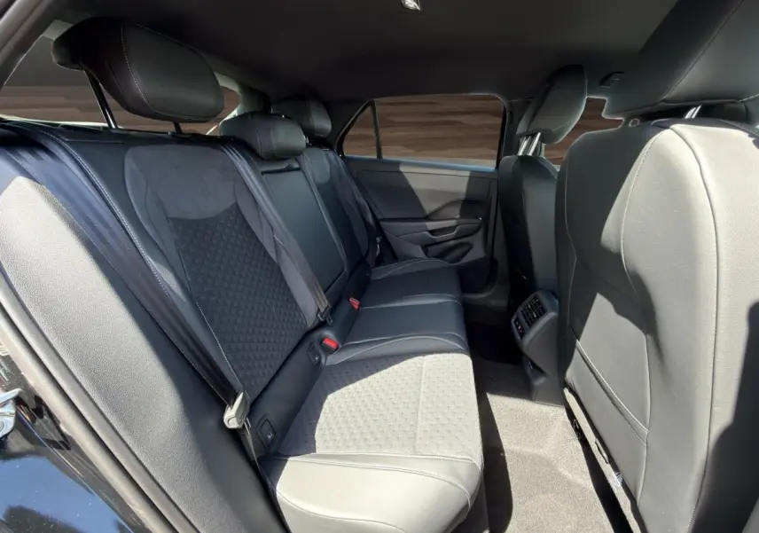 Vue intérieure côté droit des sièges arrière noirs du Volkswagen T-Roc 1.5 eTSI R-Line avec accoudoir central et aérateurs.