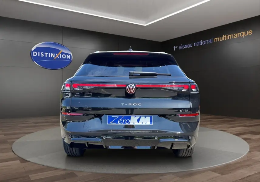 Vue arrière d'un Volkswagen T-Roc noir 2026 avec feux LED et attelage visible dans un showroom.