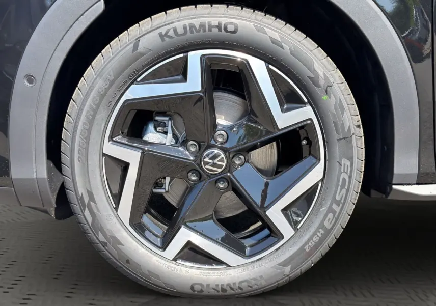 Gros plan sur la roue avant droite noire du Volkswagen T-Roc 1.5 eTSI EVO2 avec jante alliage et logo VW central.