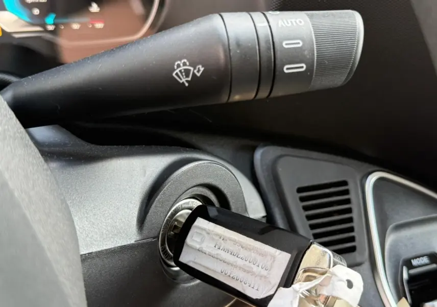 Gros plan sur la clé insérée dans le contact d'un Iveco Daily 2.3 blanc, avec commande d'essuie-glace visible.