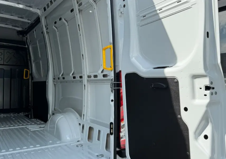 Vue intérieure arrière du fourgon Iveco Daily blanc 2026, montrant la porte ouverte avec poignée jaune et espace de chargement vide.