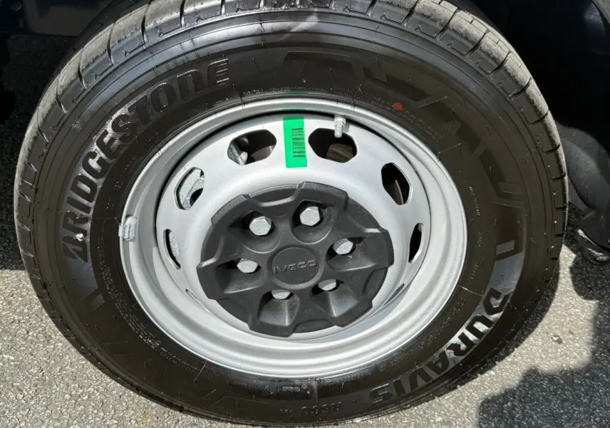 Gros plan sur la roue avant droite d’un Iveco Daily blanc, pneu Bridgestone et jante acier grise avec cache central noir.