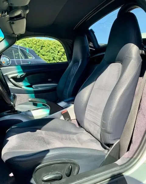 Intérieur de la Porsche Boxster 986 3.2 S gris de 2001, vue côté conducteur montrant les sièges en tissu et cuir.