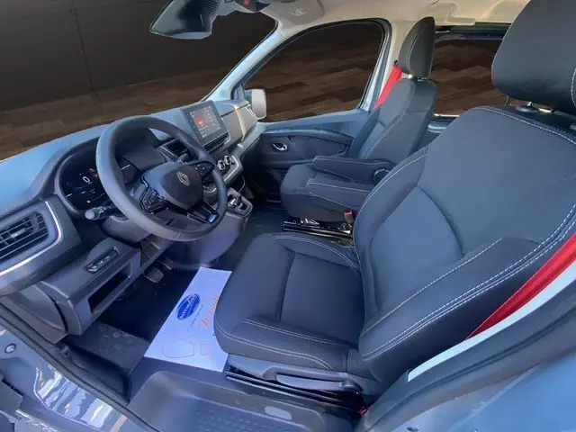 Vue intérieure côté conducteur du Renault Trafic cabine approfondie gris urbain, sièges noirs et tableau de bord moderne.