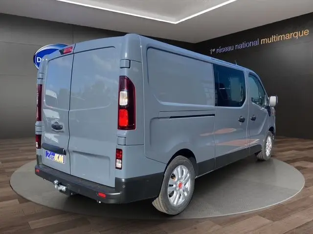 Vue 3/4 arrière droite d’un Renault Trafic Cabine Approfondie gris urbain avec jantes alliage 17'' et attelage visible.