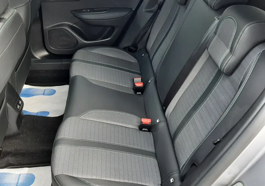 Vue latérale droite de l'intérieur arrière du Peugeot 2008 gris 2021, sièges en tissu et cuir noir avec surpiqûres vertes.
