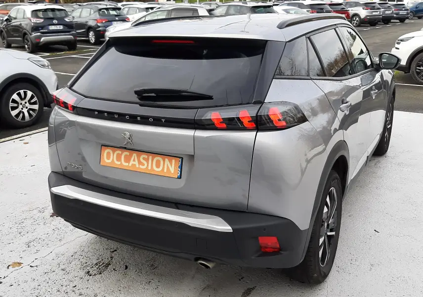 Vue 3/4 arrière droite d'un Peugeot 2008 gris 2021 avec feux arrière à griffes et toit noir contrasté.