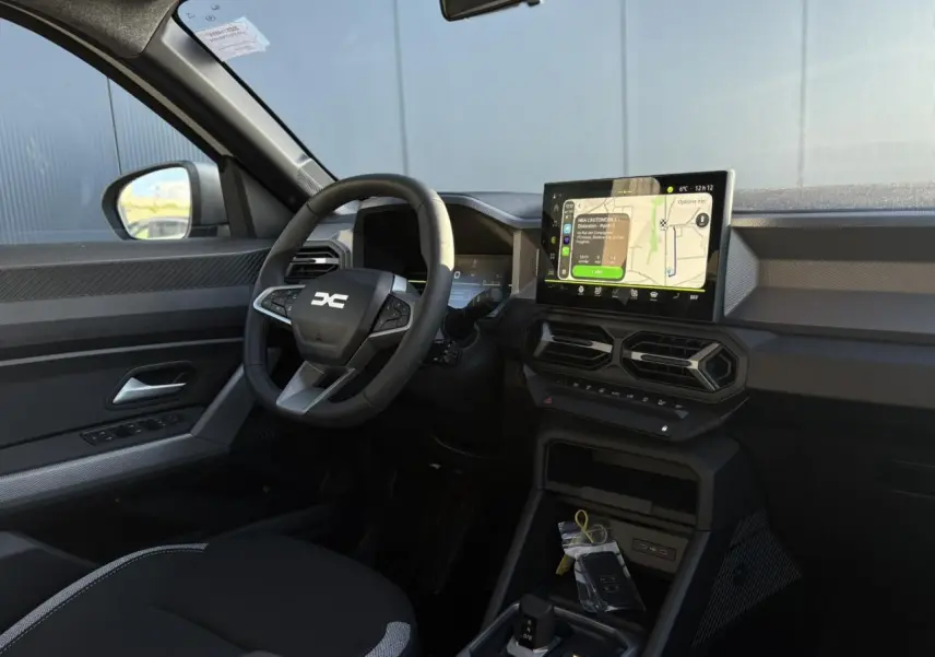 Vue intérieure côté conducteur du Dacia Duster 2026 avec tableau de bord digital et écran tactile central.