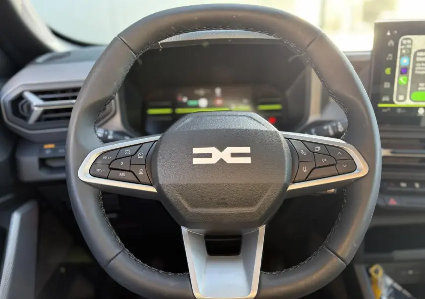 Volant noir avec commandes intégrées, vue frontale du poste de conduite du Dacia Duster 2026 blanc Glacier.