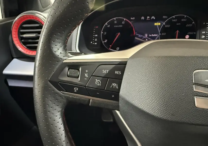 Gros plan sur le volant cuir et alu noir de la SEAT Ibiza 2024, avec commandes multifonctions et tableau de bord numérique.